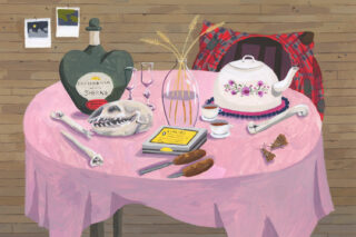 Vaaleanpunaisella pyöreällä pöydällä teekannu ja astioita.