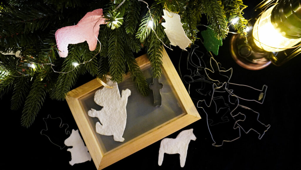 Christmas decorations made of paper on fir tree branches.