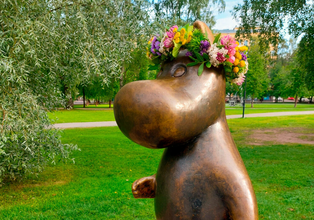 A bronze Moomintroll statue with a wreath.